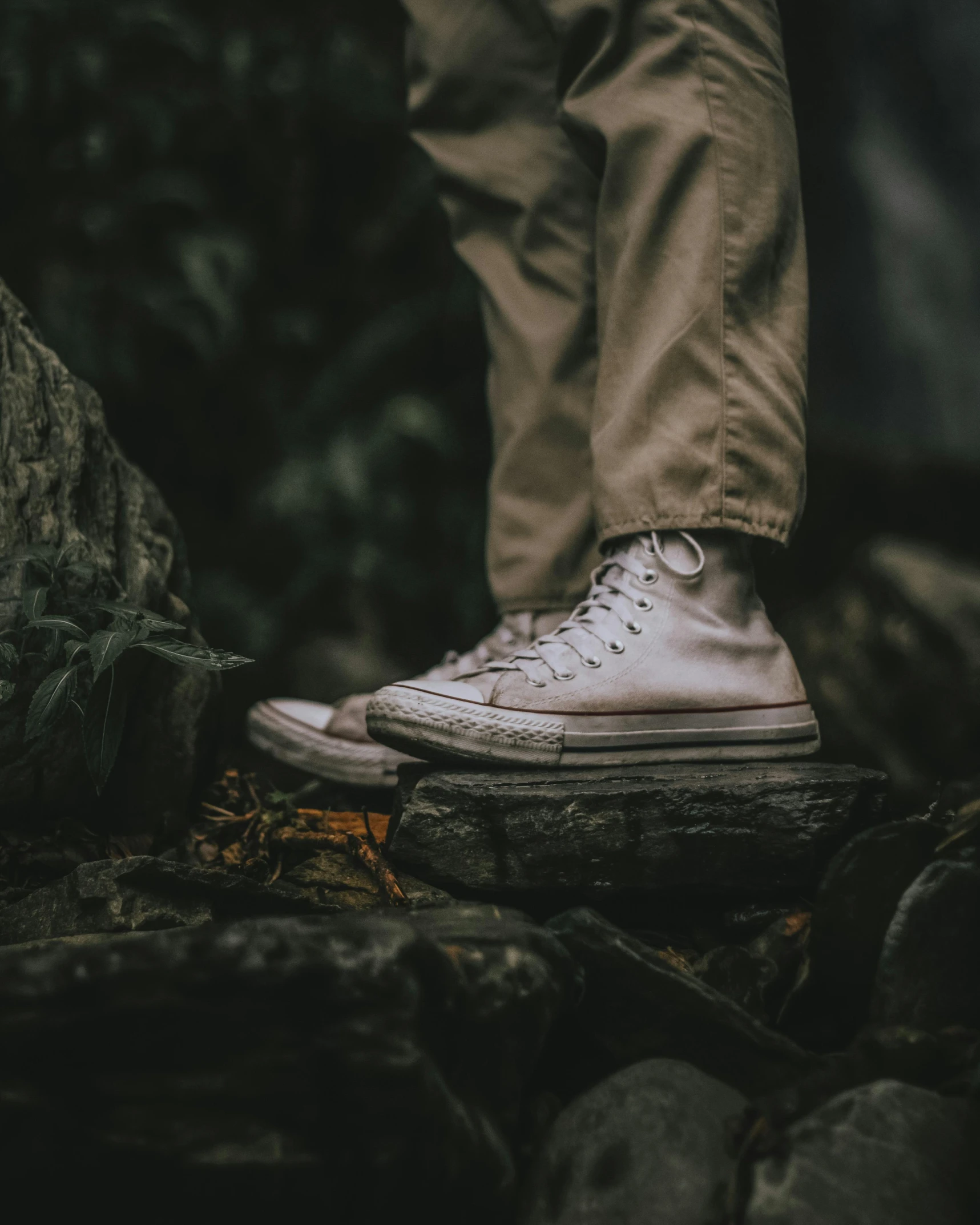 a pair of white sneakers sitting on top of a rock