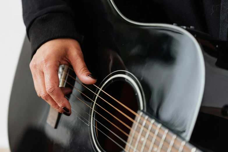 person's hand and fingers holding an electric guitar