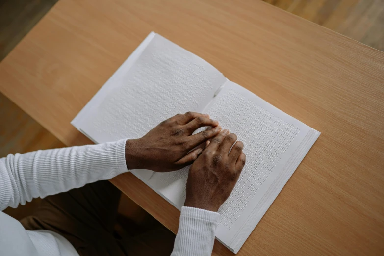 an older person holds the hands of another hand over a book