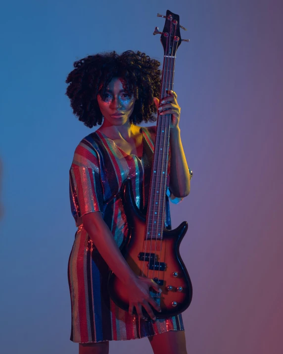 a woman holding a black guitar with blue background