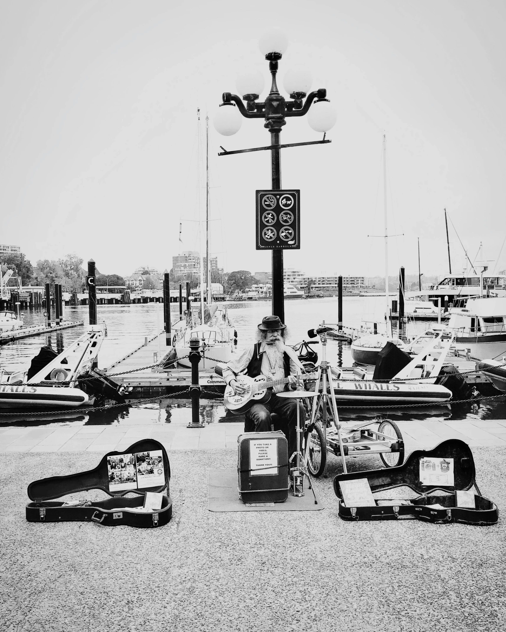 two men sitting on a motorcycle next to various boats