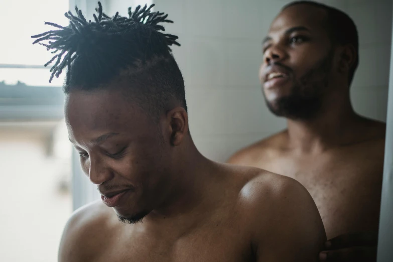 two young black men standing in front of a bathroom mirror