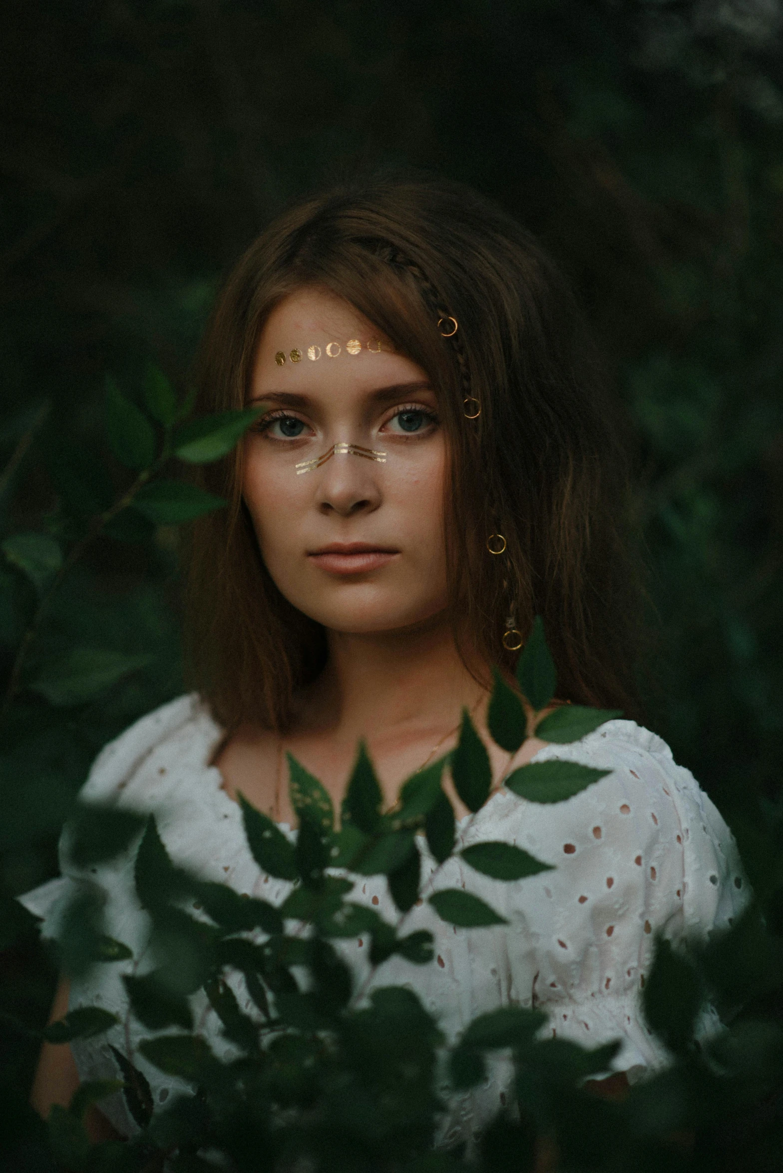 a woman standing in a forest with her head tilted to the side