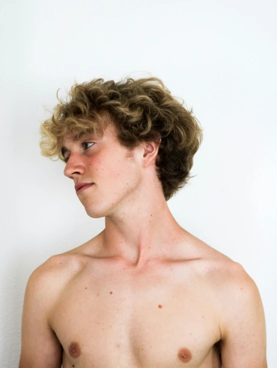 young shirtless man with  posing in front of white wall