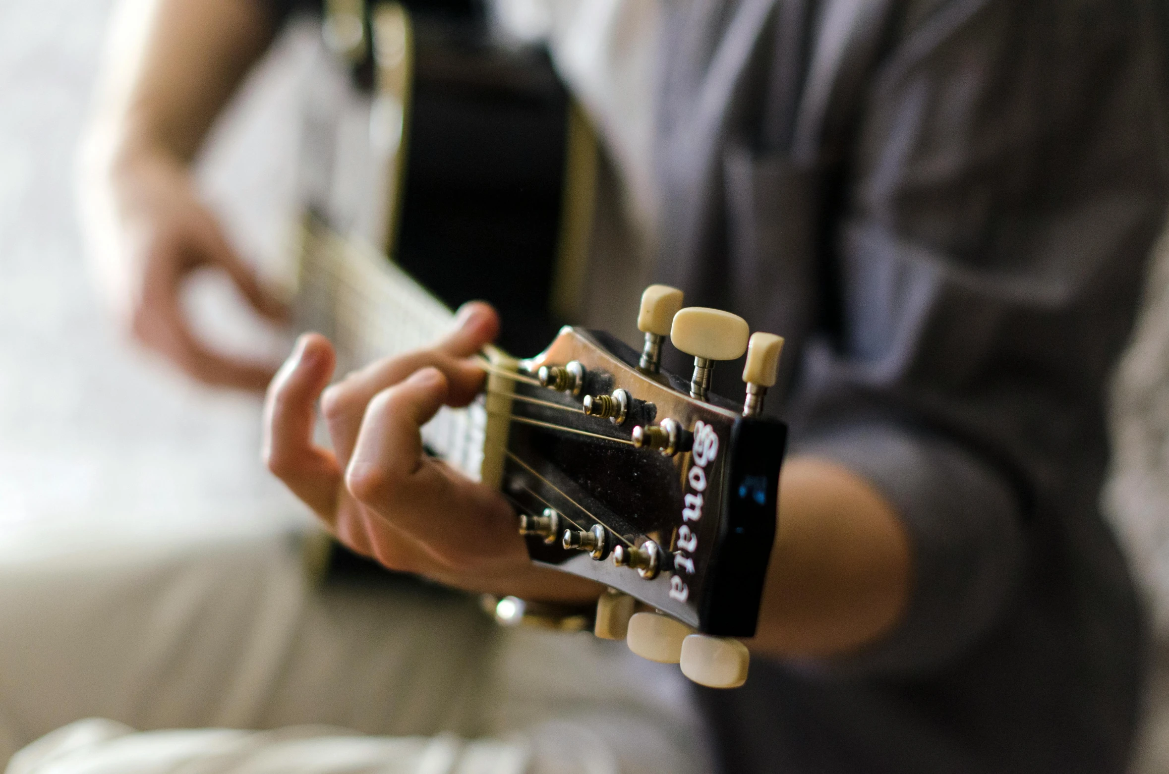 a person sitting holding an acoustic guitar