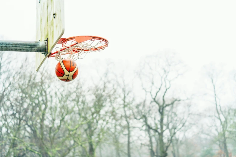 there is a basketball in the basket while a basketball flies by