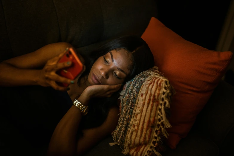 woman laying down on couch and taking po with cellphone