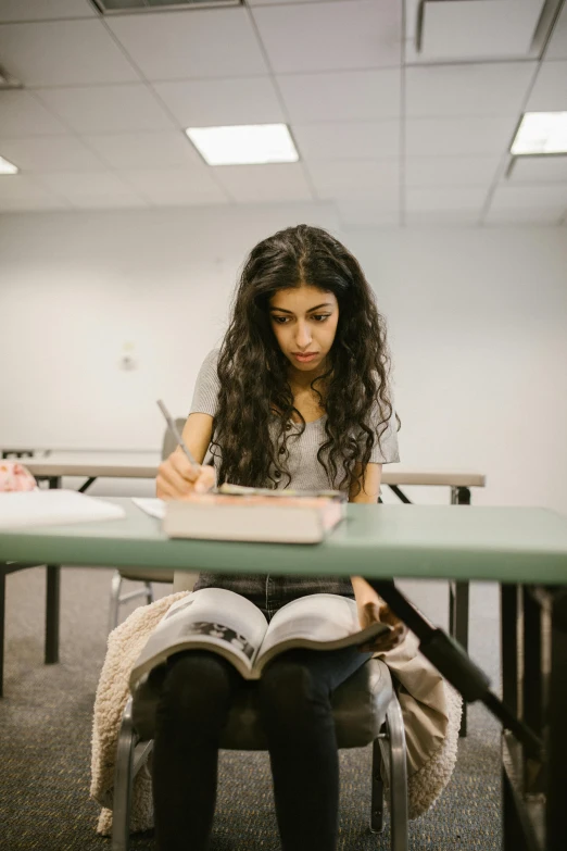 a young woman writing on her notebook in front of a desk