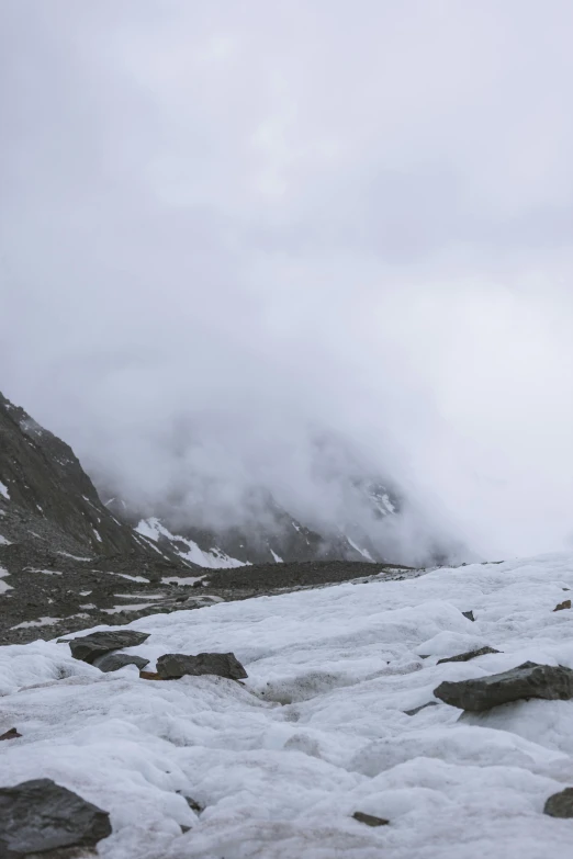 a mountain covered in snow with low lying clouds