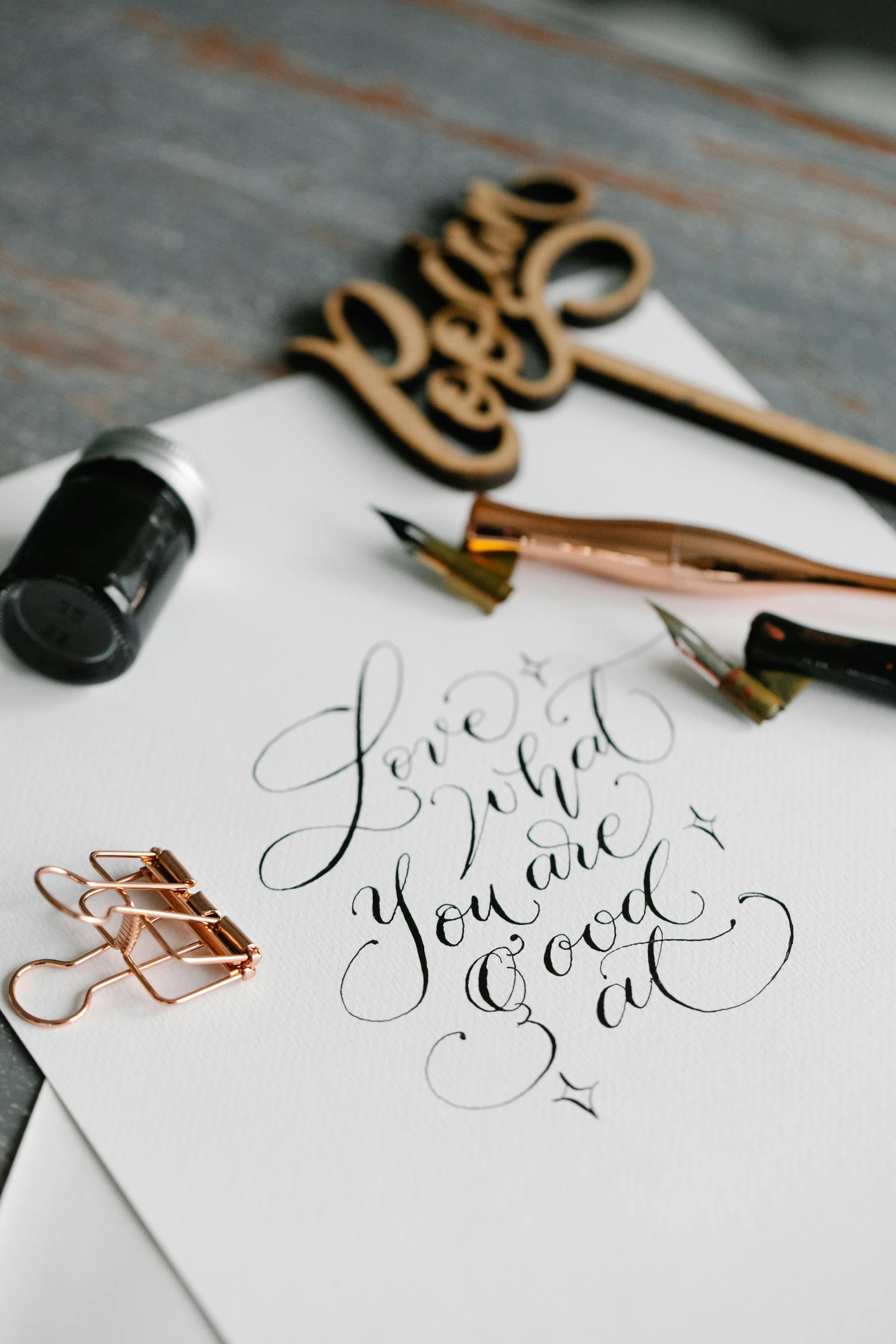 scissors, paper clips and calligraphy on top of a white piece of paper