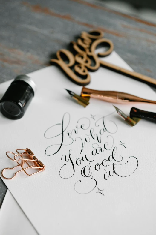 scissors, paper clips and calligraphy on top of a white piece of paper