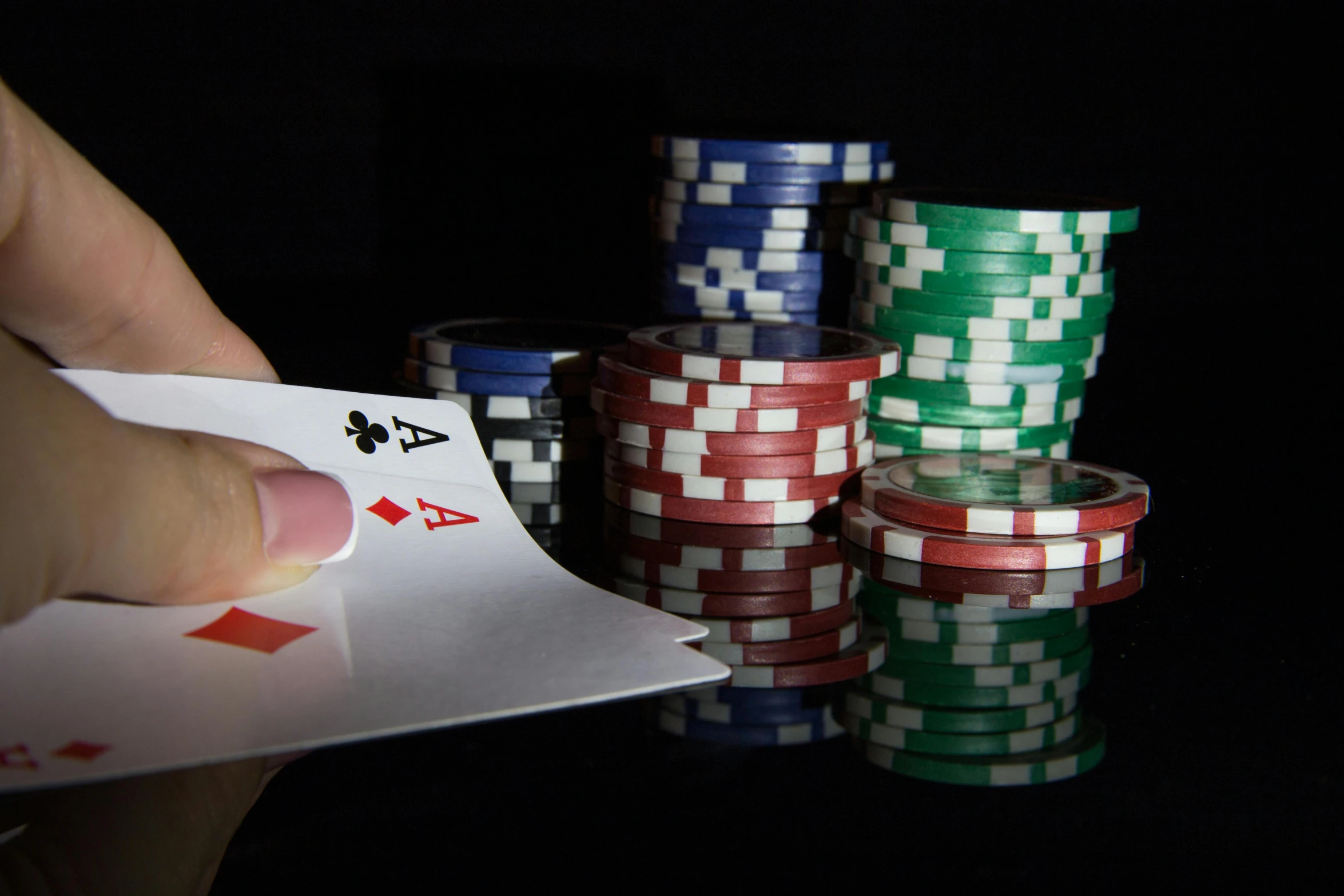 a person holding up playing cards near piles of chips