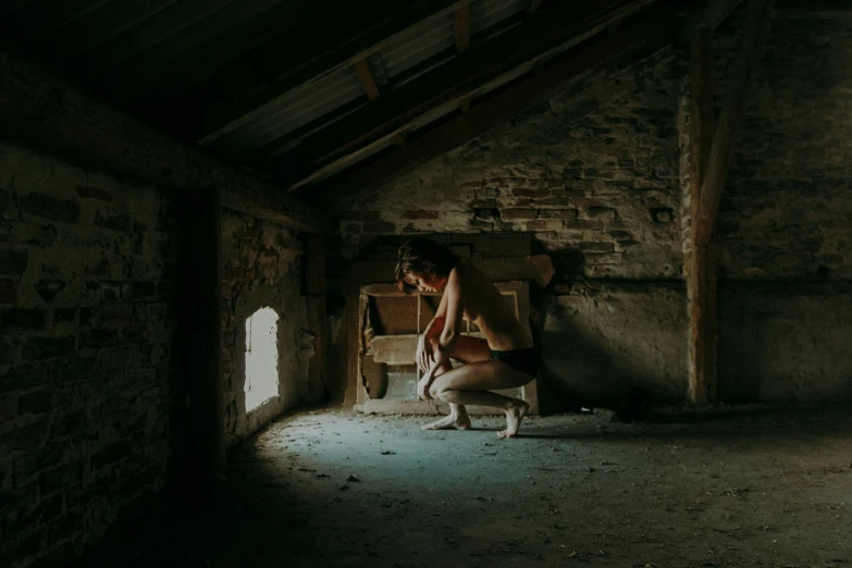 a man kneeling down in the corner of an empty room