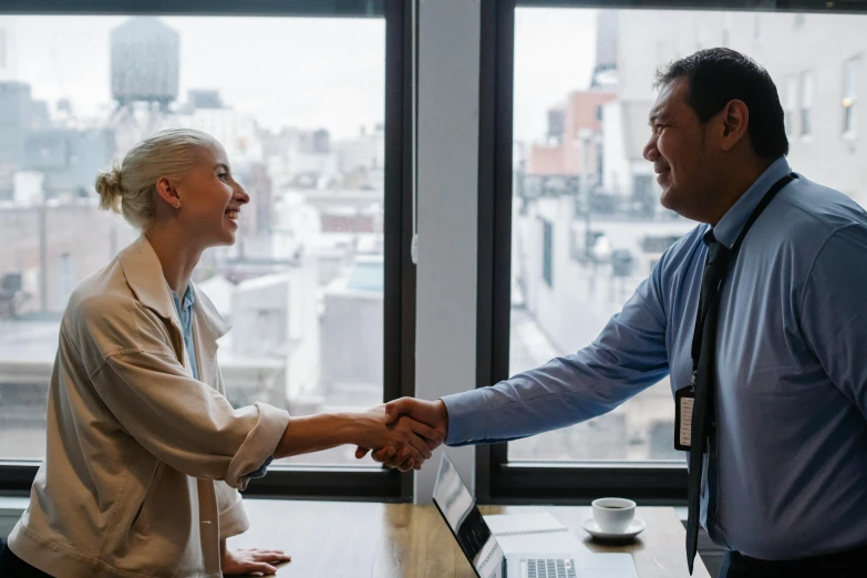 two people are shaking hands in front of the city