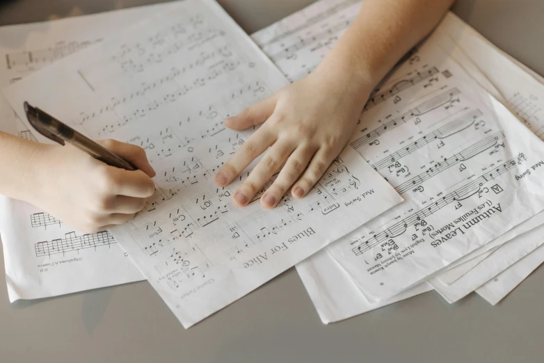 someone using their hands on music sheet paper