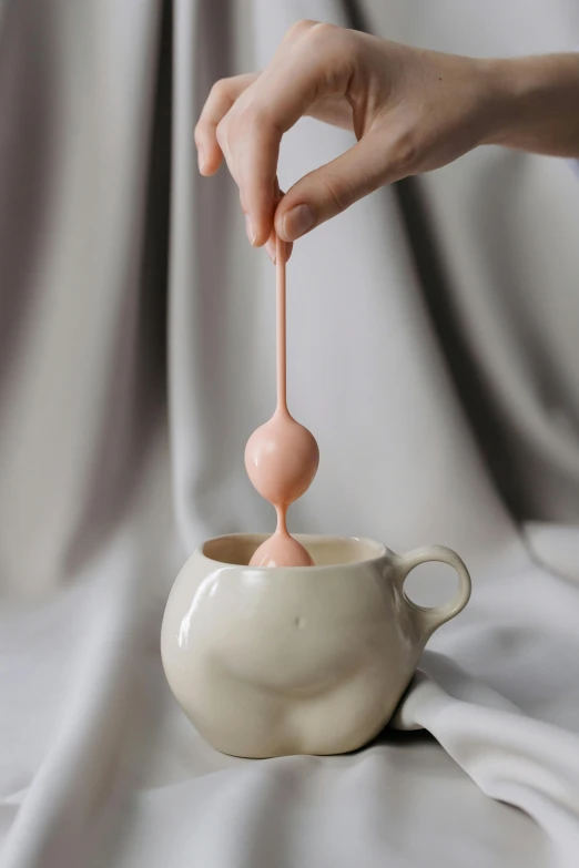 a white vase with a drop of pink liquid