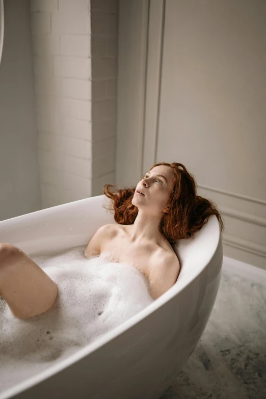 a beautiful woman lying in a tub with her hair blowing back