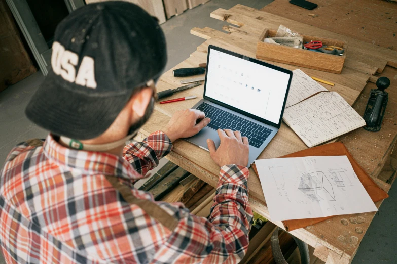 a man using a laptop computer on a wooden table