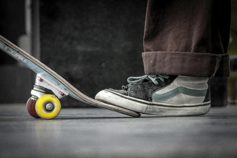 person's foot on top of skateboard that has yellow wheels