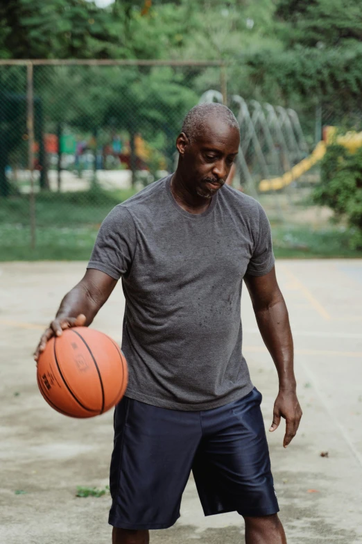 a man holding a basketball and looking down on the ground