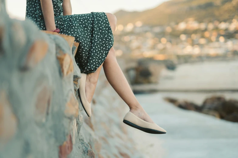 the woman sits on a wall with her feet on her back