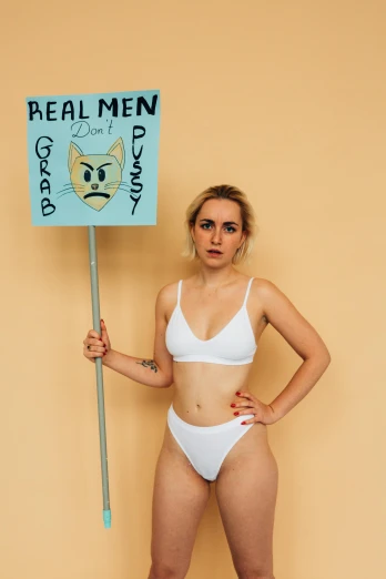 a woman posing in underwear while holding a sign