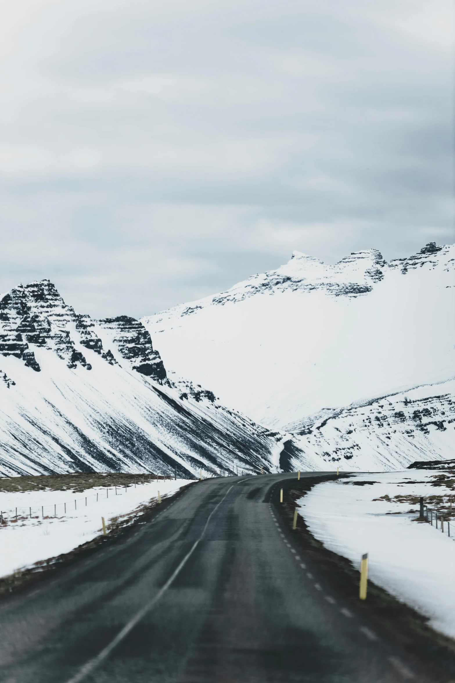 the mountains covered in snow and a road is empty