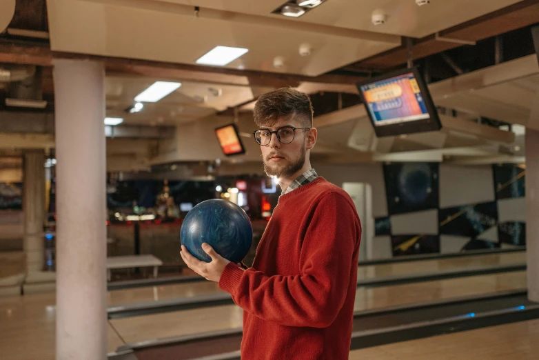 a man is holding a bowling ball in the mall