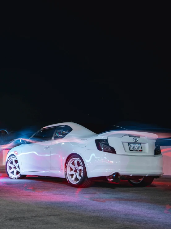 two white cars parked side by side at night