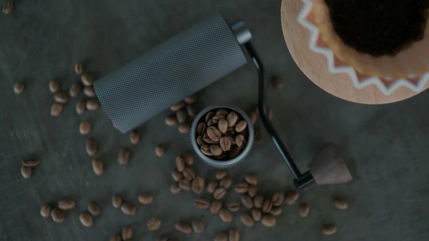 a coffee grinder sitting next to a mug of coffee on top of coffee beans