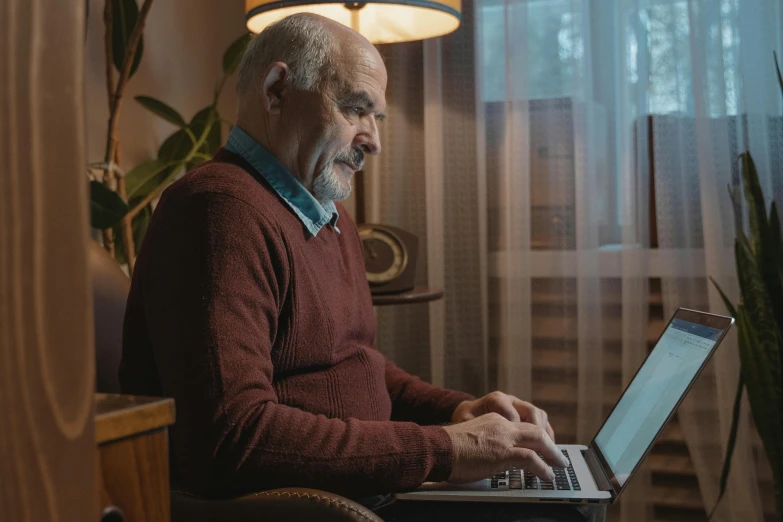 an old man using a laptop in a chair