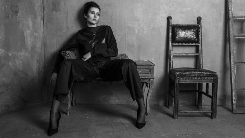 black and white pograph of woman sitting on an old chair