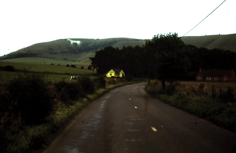 a wet country road that has houses and hills