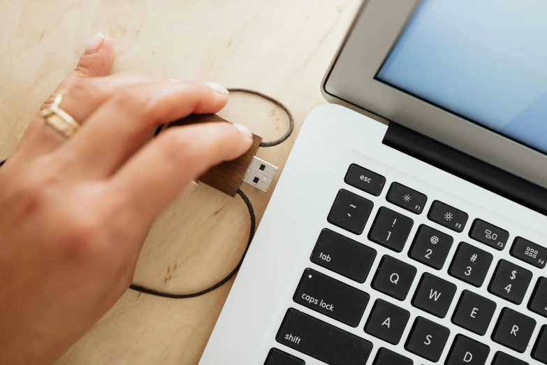 someone holding the flash drive next to their laptop