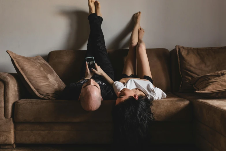 two people lying on top of a couch on their stomachs