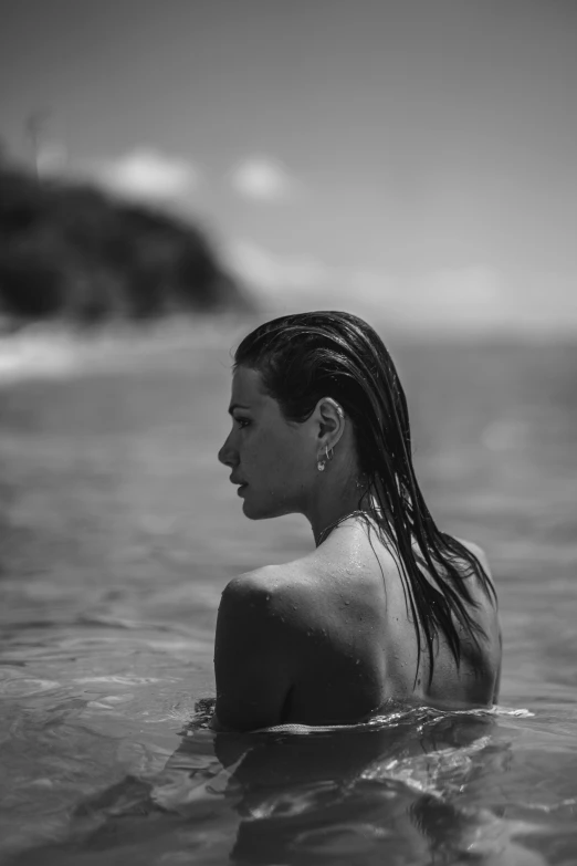 a woman swims in the ocean looking at the shore