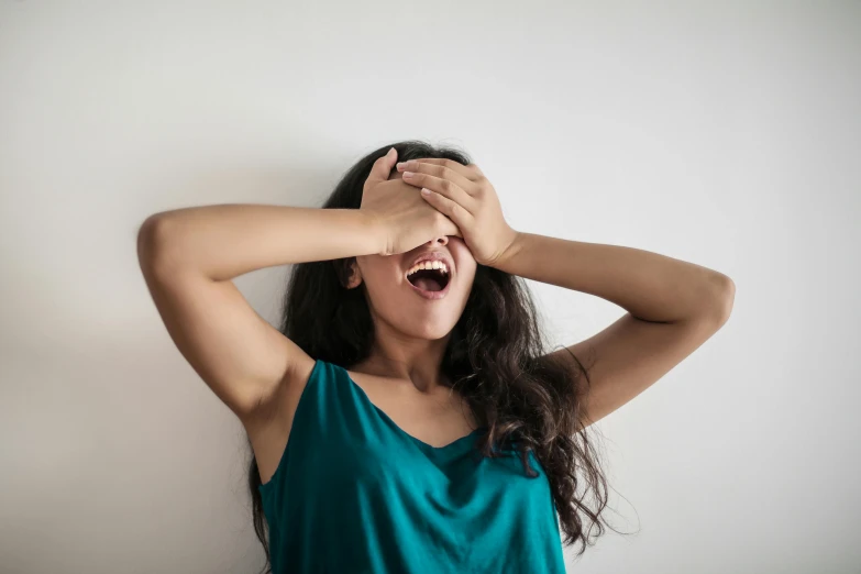 a woman is holding her head near her ears and covering her eyes with one hand