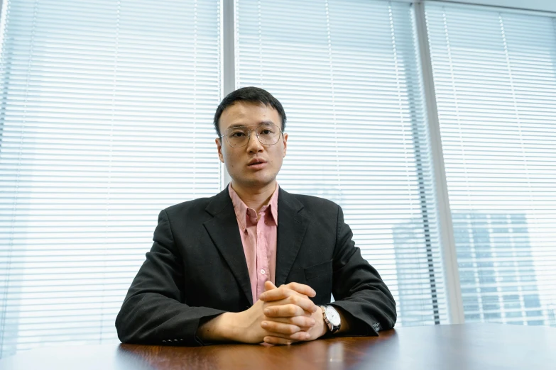 man in black suit sitting at table with hands crossed