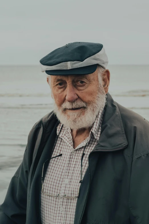 an old man with white hair and a beard standing by the ocean