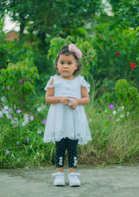 small girl dressed in a white dress standing on the side of a road