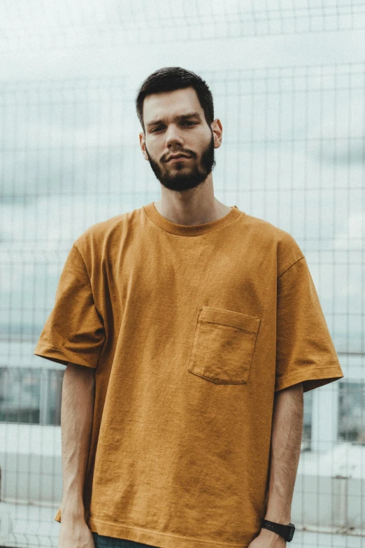 a man with a beard stands against a glass wall