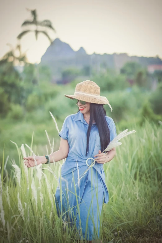 a woman in a hat walking through tall grass