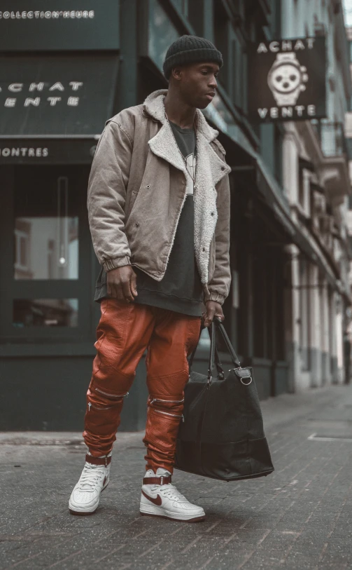 a man is standing on the street while holding a hand bag