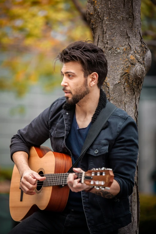 a man that is sitting on the ground with an guitar