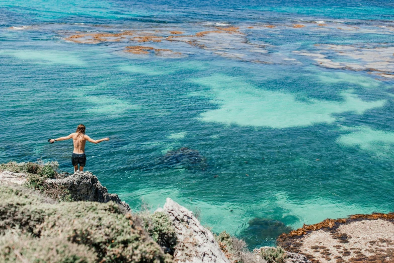 a man is standing on a cliff overlooking the ocean