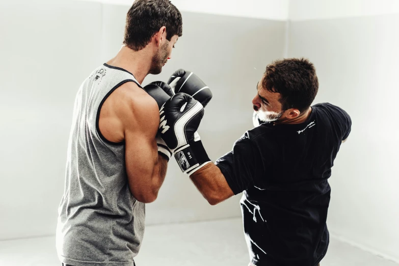 two men in a boxing ring one wearing gloves and the other holding a punching glove