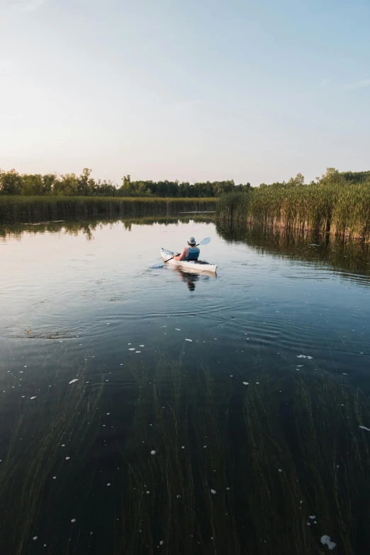 a man paddling his kayak through the water in a lake