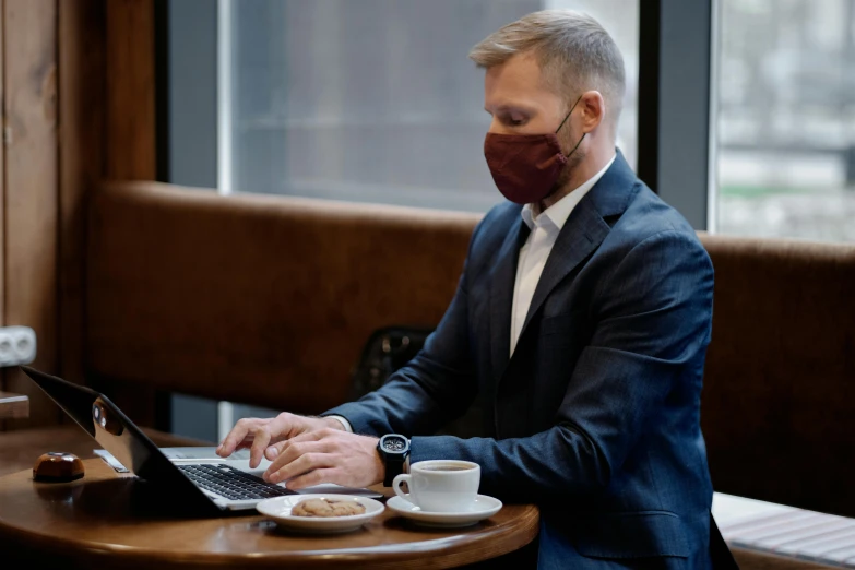 a man with a face mask on uses a laptop