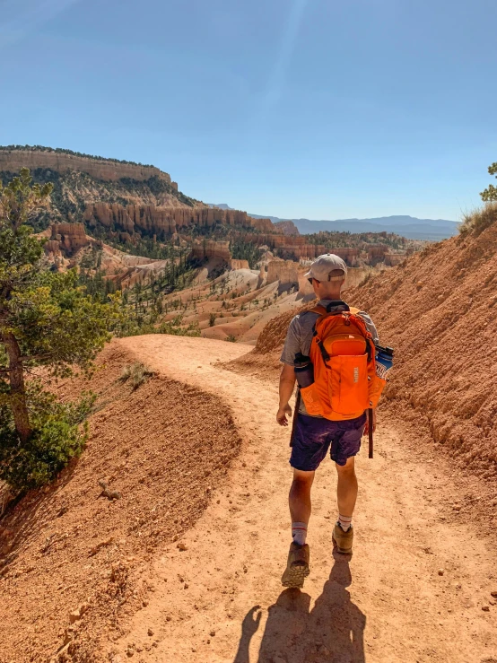 a person with backpack and shoes standing on dirt road