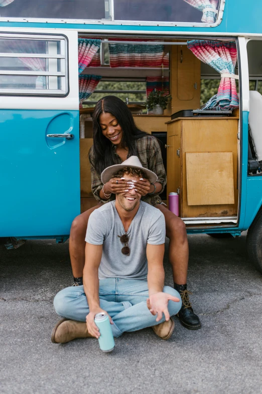 a man and woman sitting down outside of a blue van